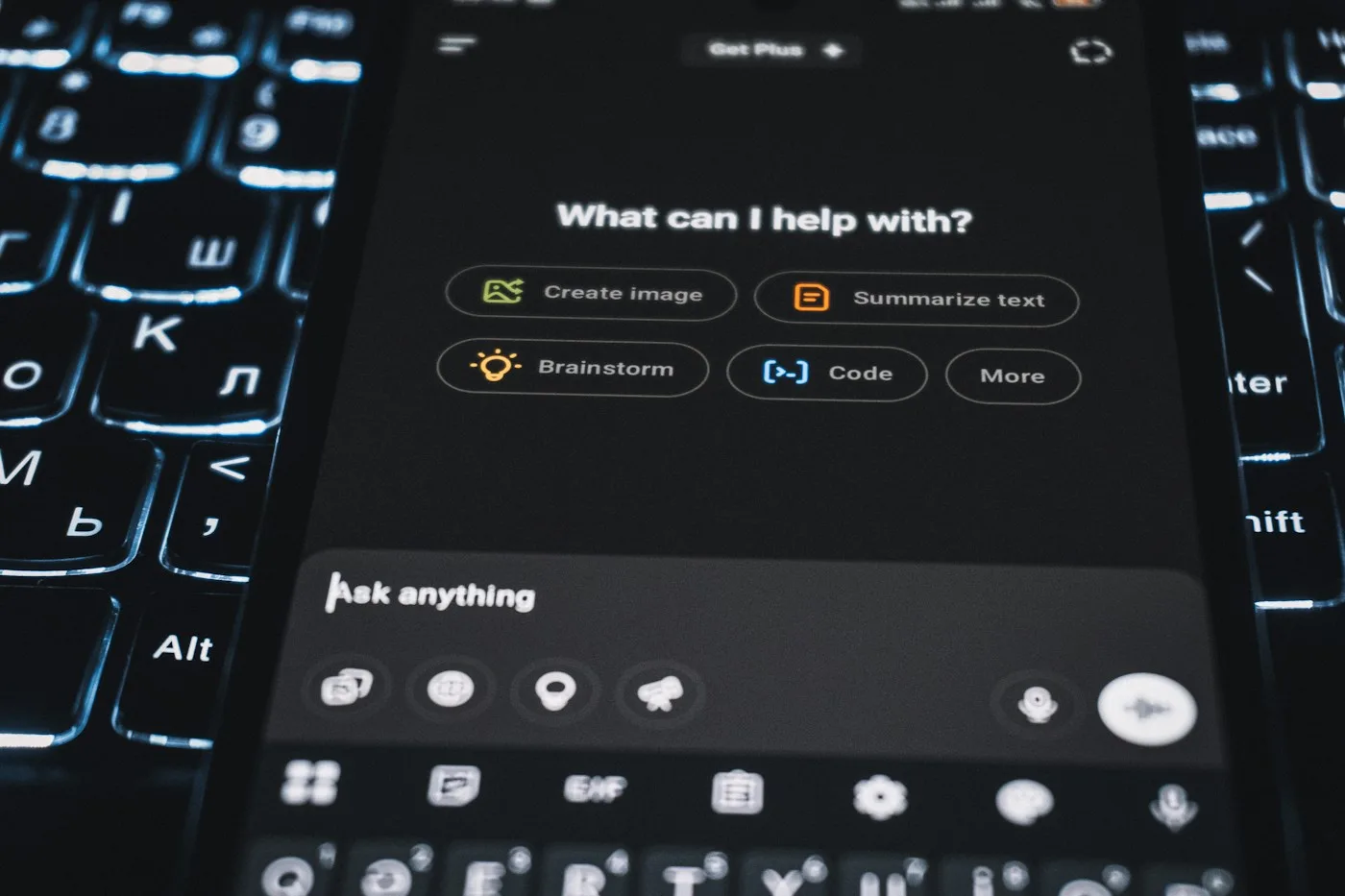 A smartphone displaying ChatGPT on top of an illuminated keyboard