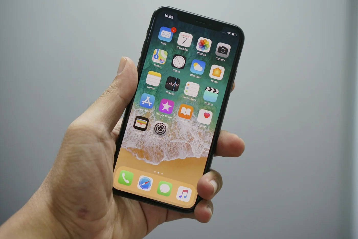 A hand holding an iPhone with a grid of app icons