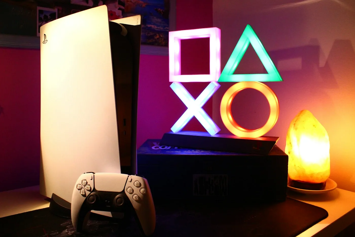 A PlayStation 5 beside a glowing PlayStation-symbol lamp