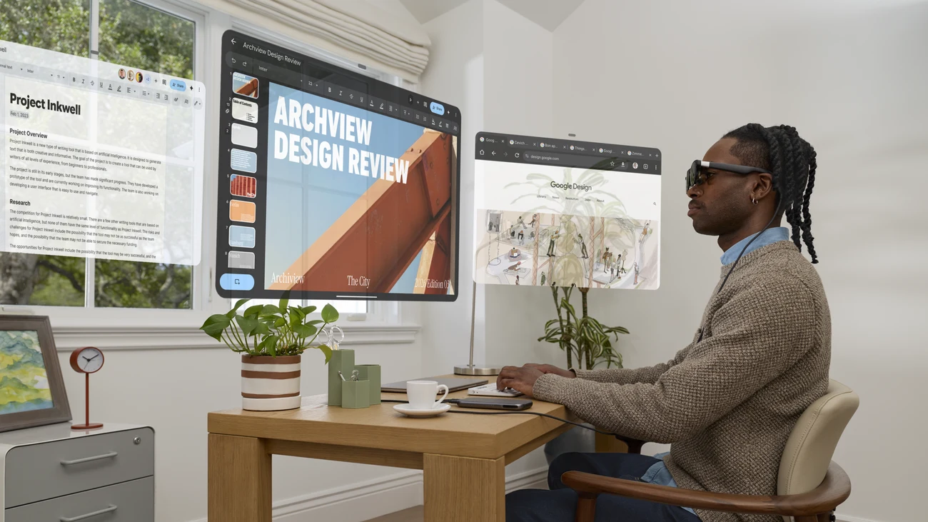 A person wears XREAL Aura at a desk beside a promotional visualization of floating app windows.